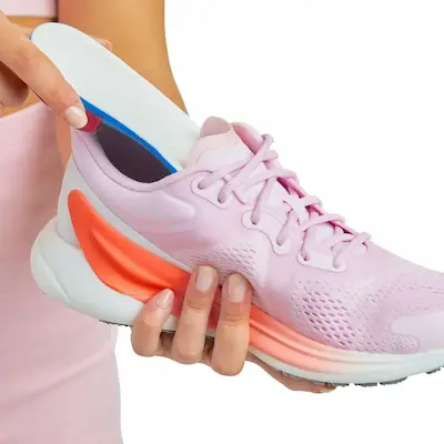 Custom foot orthotic being placed inside an athletic shoe